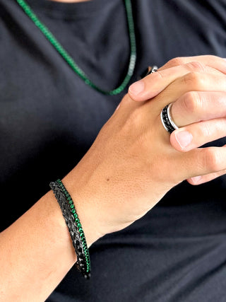 Pulseira masculina em aço inox black com zircônias verdes estilo esmeralda da UNA Semijoias e Aço no pulso masculino, combinada a anéis em aço, em foto de lifestyle.