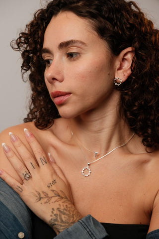 Brinco redondo com pontos de cristal em prata 925, acabamento polido e design delicado, leve e hipoalergênico.