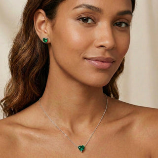 Brinco coração verde banhado a prata 925 da UNA Semijoias & Aço na orelha feminina, foto lifestyle com colar combinando, fundo neutro.
