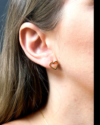 Brinco delicado em formato de coração vazado banhado a ouro 18k da UNA Semijoias e Aço na orelha feminina em close lateral