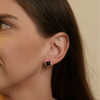 modelo usando Brinco pequeno flor preto banhado a prata 925 da UNA Semijoias e Aço em fundo branco, semijoia atemporal delicada para uso diário e revenda.