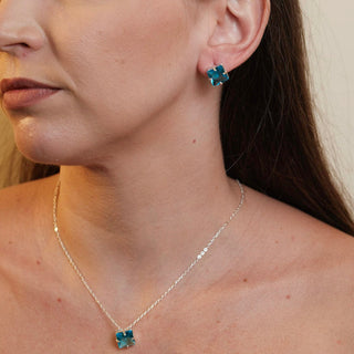 Brinco pequeno com pedra de vidro verde quadrada banhado a prata 925 da UNA Semijoias e Aço em fundo branco, semijoia hipoalergênica para uso diário.