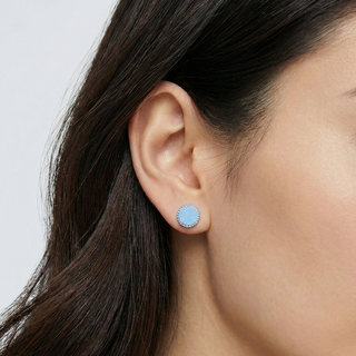 Brinco redondo branco banhado a prata 925 da UNA Semijoias e Aço em fundo branco, semijoia antialérgica delicada ideal para uso no dia a dia.