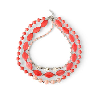 Choker maxi de bijuteria fina em resina coral com várias voltas e estrelas-do-mar metálicas da UNA Semijoias e Aço em fundo branco.