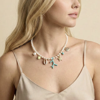 Choker de bijuteria fina com contas tipo pérola e pingentes do mar coloridos em resina e metal dourado da UNA Semijoias e Aço em fundo branco.
