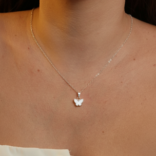 Colar borboleta branca banhado a prata 925 da UNA Semijoias e Aço em fundo branco, com pingente de borboleta clara e corrente fina centralizada.