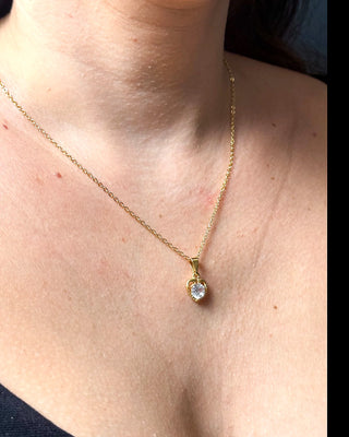 Colar coração cravejado banhado a ouro 18k da UNA Semijoias e Aço no colo feminino em close, com pingente em forma de coração com pedra central em destaque.