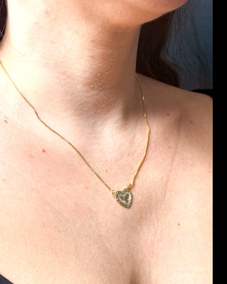 Colar coração religioso Espírito Santo folheado a ouro 18k da UNA Semijoias e Aço no colo feminino em close, com pingente delicado em destaque.
