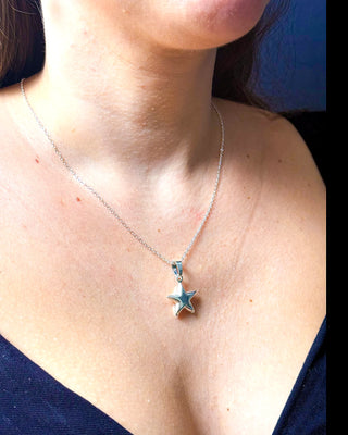 Colar estrela banhado a prata 925 da UNA Semijoias e Aço no colo feminino em close, com pingente de estrela lisa em destaque.