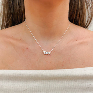 Colar infinito com zircônias banhado a prata 925 da UNA Semijoias & Aço em fundo branco, corrente delicada e pingente sofisticado em destaque.