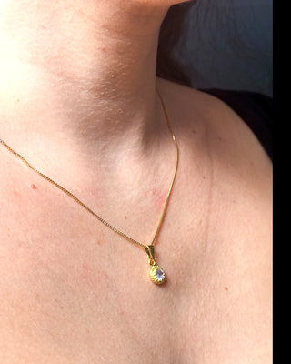Colar ponto de luz banhado a ouro 18k da UNA Semijoias e Aço no colo feminino em close, com pingente redondo cravejado em destaque.