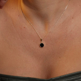 Colar redondo pequeno preto banhado a prata 925 da UNA Semijoias e Aço em fundo branco, semijoia antialérgica delicada com pingente circular preto.