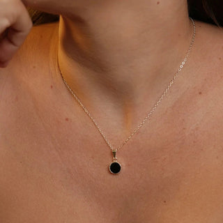 Colar redondo pequeno preto banhado a prata 925 da UNA Semijoias e Aço em fundo branco, semijoia antialérgica delicada com pingente circular verde.