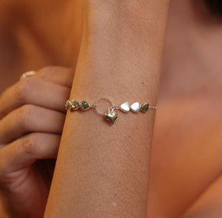 Pulseira com corações lisos e pingente central banhada a prata 925 da UNA Semijoias e Aço em fundo branco, em vista frontal.