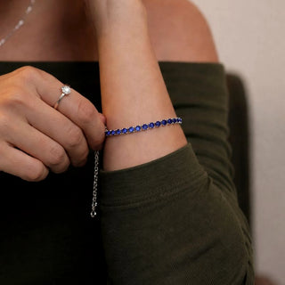 Pulseira riviera azul banhada a prata 925 da UNA Semijoias e Aço no pulso feminino, em close, com brilho delicado e corrente ajustável em destaque